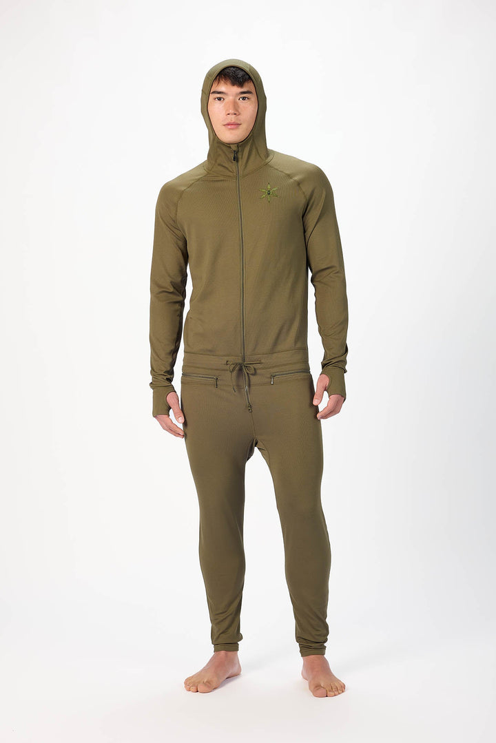 A man wearing a olive onesie with a hooded zip-up jacket and jogger pants, standing against a plain white studio background.