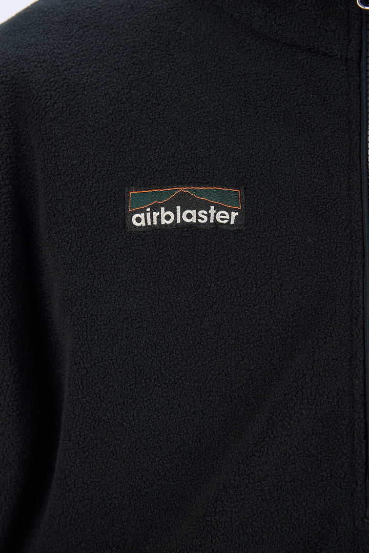 Close-up of a black fleece pullover jacket with a small embroidered Airblaster logo on the chest.