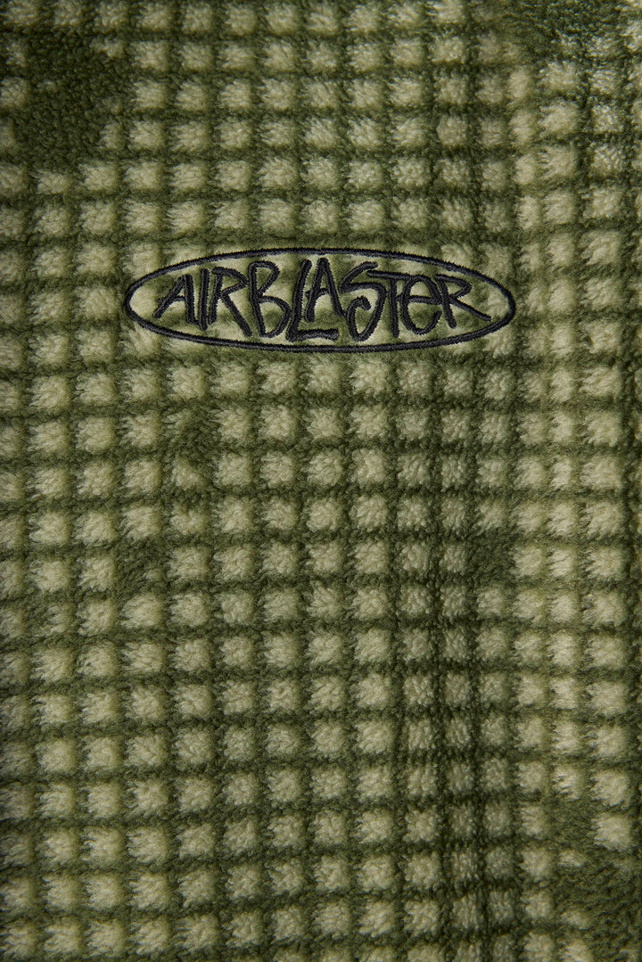 Close-up of a textured waffle fleece blanket in olive green and beige, featuring a black Airblaster logo embroidered in the center.