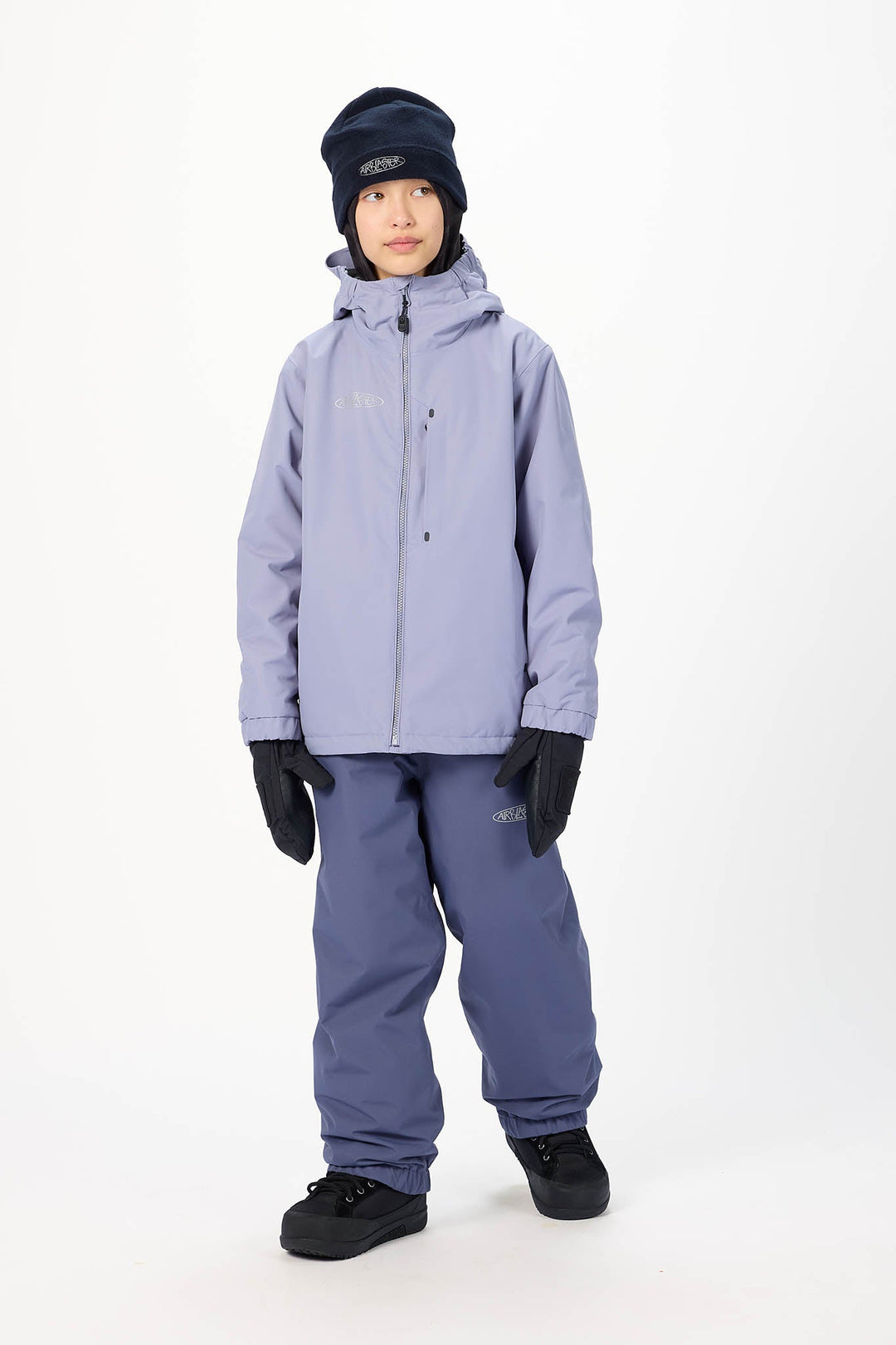 A child modeling a light purple ski jacket, matching purple snow pants, black gloves, and a dark navy beanie against a plain white studio background.
